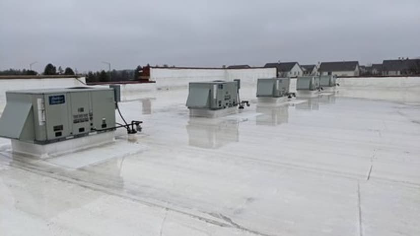 Rooftop HVAC units on a commercial building with a cloudy sky backdrop.