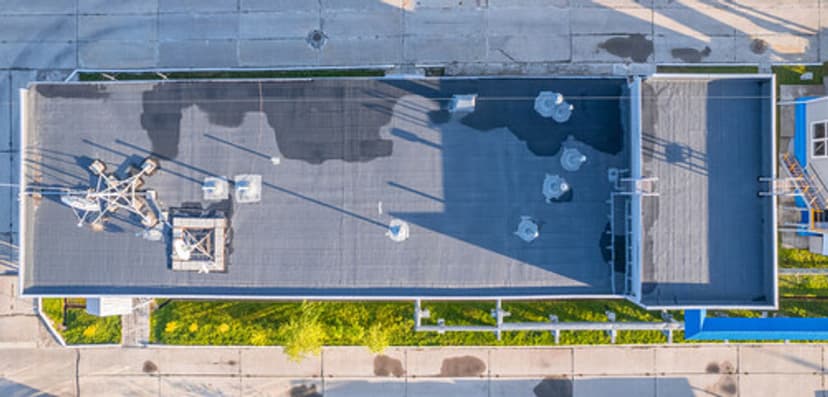 Aerial view of an industrial building roof with equipment, vents, and clear pathways.